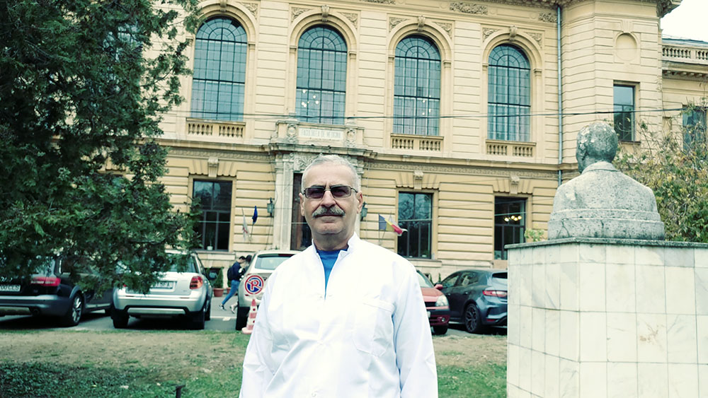 Professional portrait of Gastroenterologist Dr. Horia Marculescu, MD, in a white lab coat at his office in Bucharest. The background reflects a clinical and academic setting at Carol Davila University.