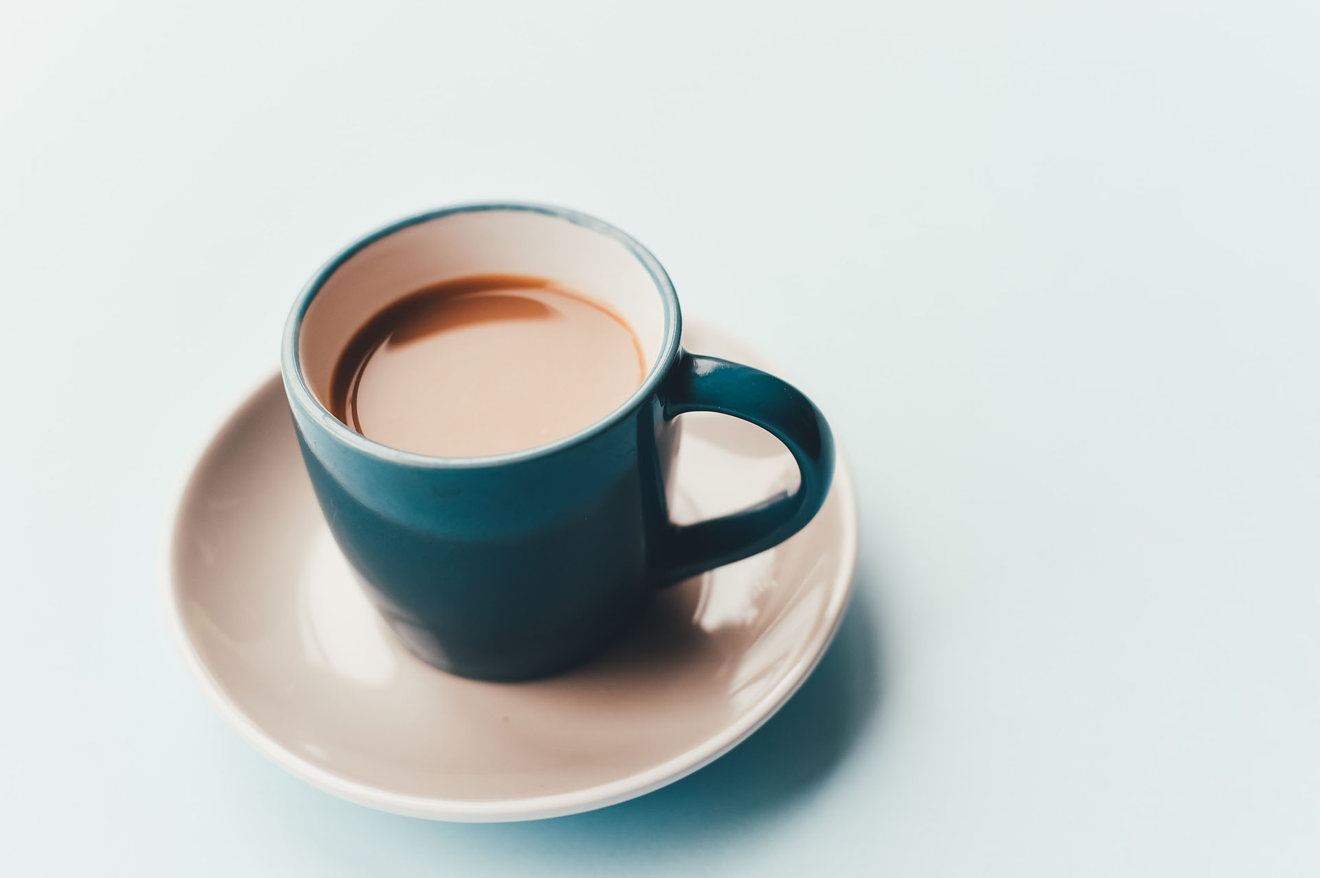 A blue cup of hot coffee is sitting on a white table, suggesting a constipation relief with a remedy made at home.
