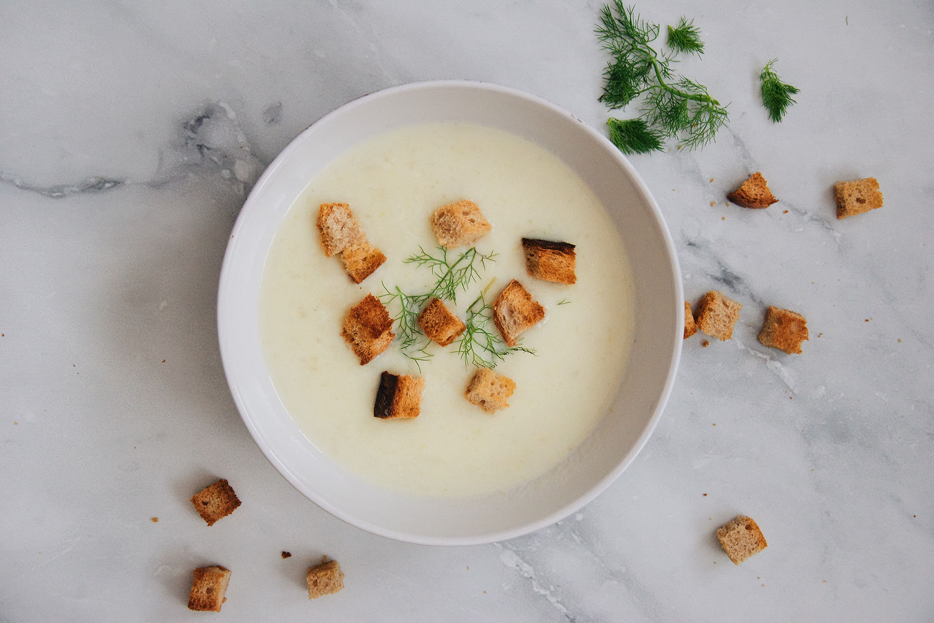 A bowl of vegetable soup was placed on a white table, suggesting constipation relief and a healthy diet.